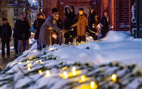 mourners leave flowers in the snow after a memorial service