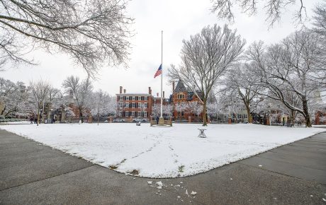 Flag being lowered to half nast on a snowy main green