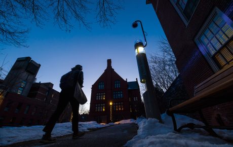 a student walks through campus lit by a security kiosk