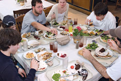 Photo of a group of students crowded around a table for a meal.