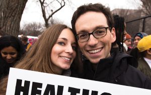 Photo of Kira Ganga Kieffer ’08 and Aaron Eisman ’08, at a rally with a sign that says 