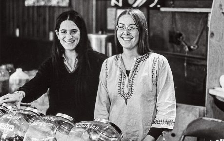 Image of Leslie Seeman and Barb Goldman standing behind the counter in the 1970's Brown University coffeeshop 