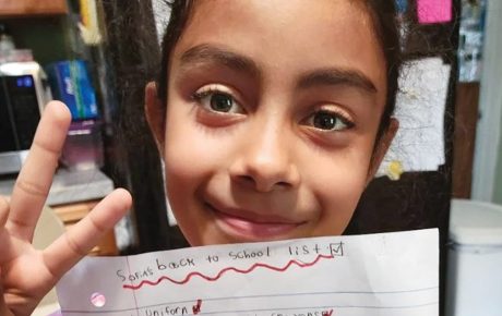 Image of a child holding up the peace sign and a piece of paper.