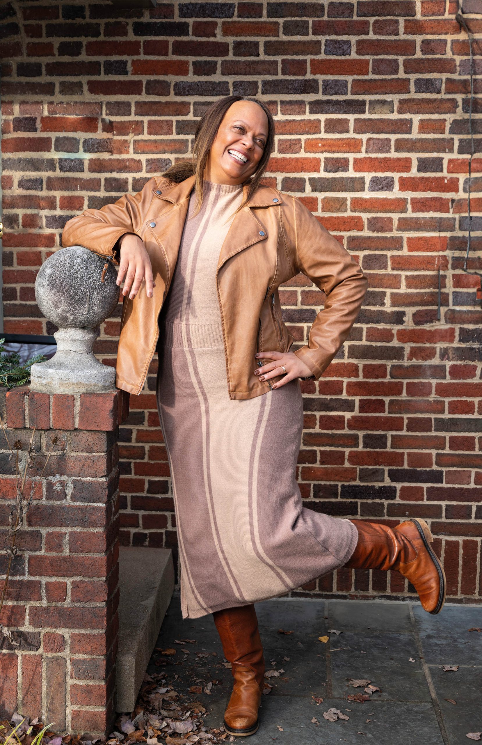 Image of Brenda Barbour smiling with her hand on her hip and a brick wall.