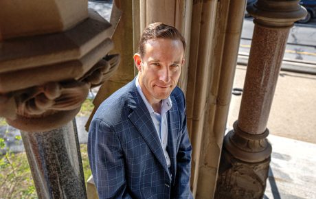 Image of John Friedman sitting in front of columns outside Robinson Hall.