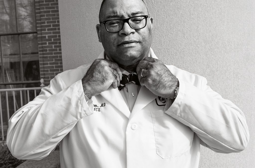 Archival black and white image of Galen Henderson tying a bowtie.