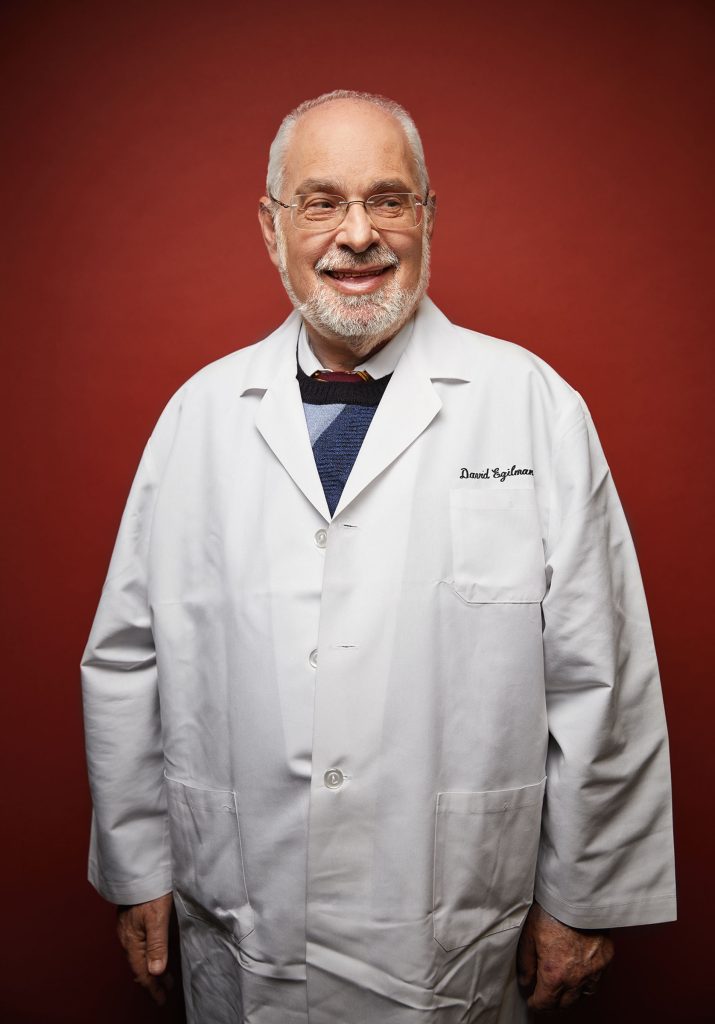 Image of David Egilman in his drs coat and a red background.