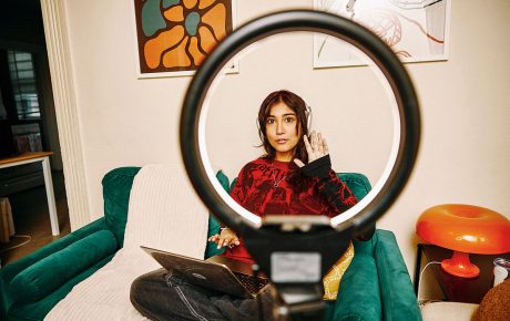 Image of Lauren Eusebio through a ring light with a laptop on her lap