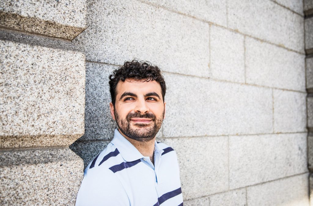 Close-up image of Aaron Gokaslan with a concrete brick wall behind him.