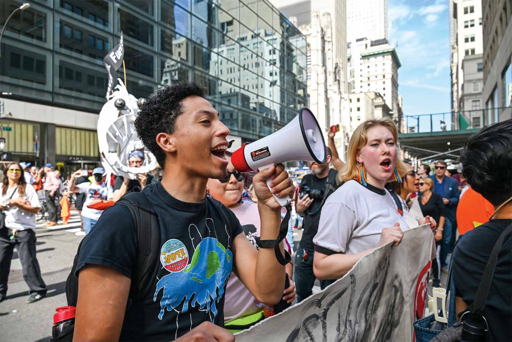 Image of individuals at a protest, one with a blowhorn.
