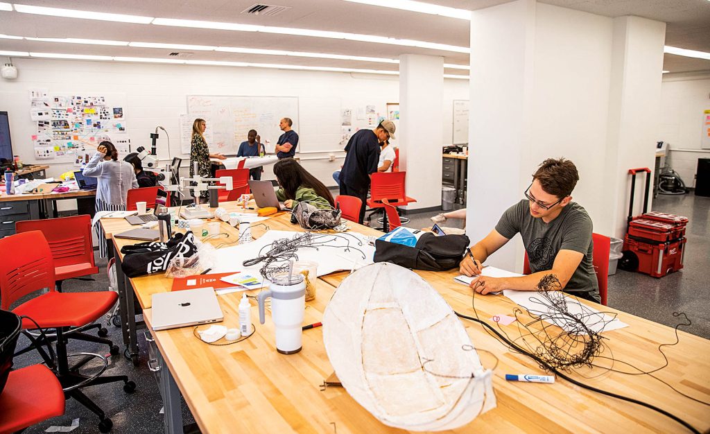 Image of students at a large table in a maker space.
