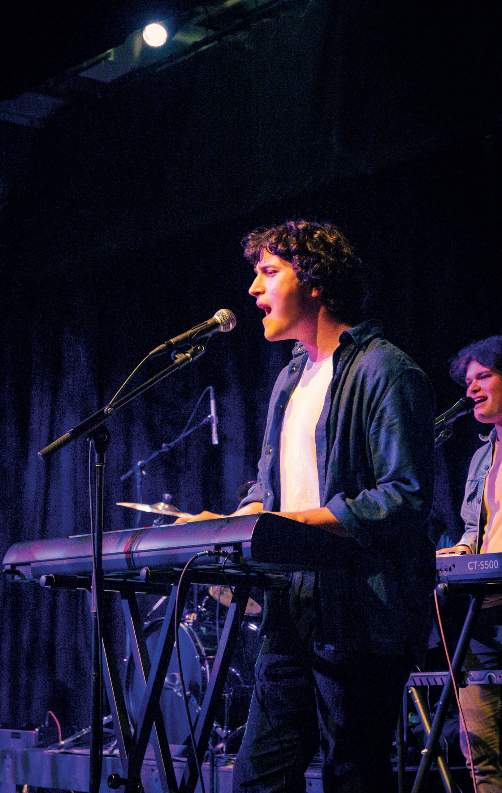 Image of Linus Lawerence singing while playing the piano on stage.